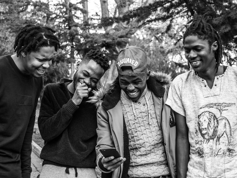 Four young men laughing together, black and white